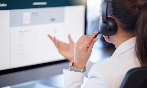 Woman wearing headset talking and looking at computer screen
