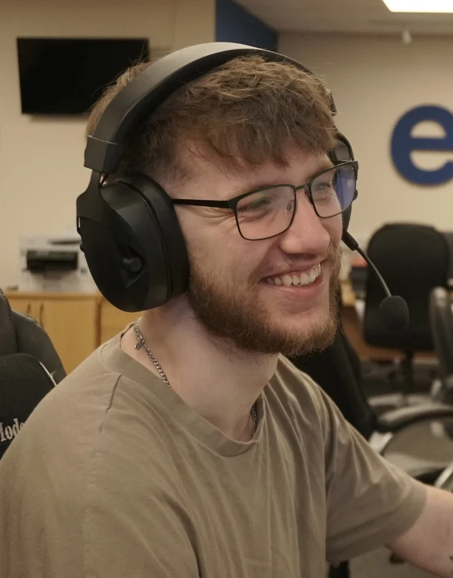 Image of a man with a computer headset on smiling